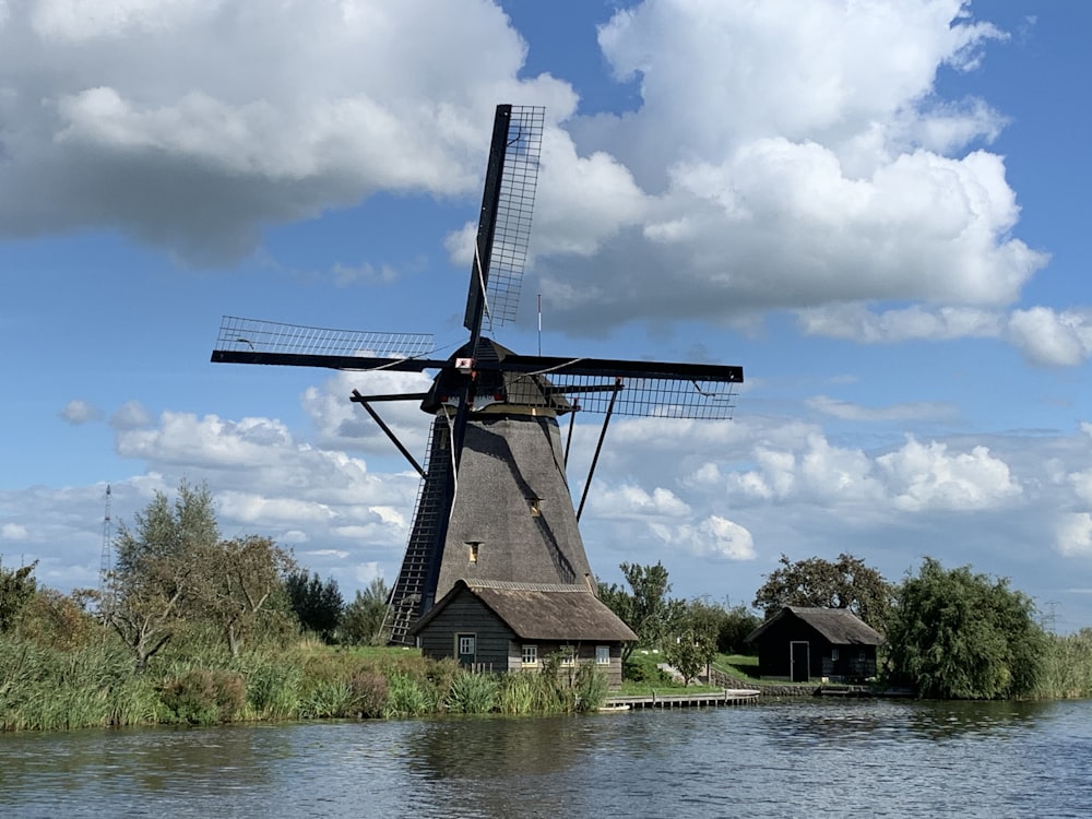 brown windmill near body of water under cloudy sky during daytime