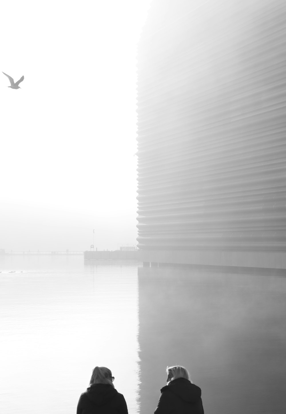 grayscale photo of man in black jacket standing on water