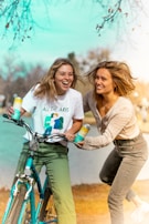 A pair of friends laughing together while sitting on a bench by the lake.