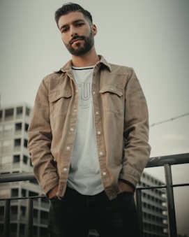 man in brown button up jacket standing near white wall