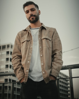 man in brown button up jacket standing near white wall