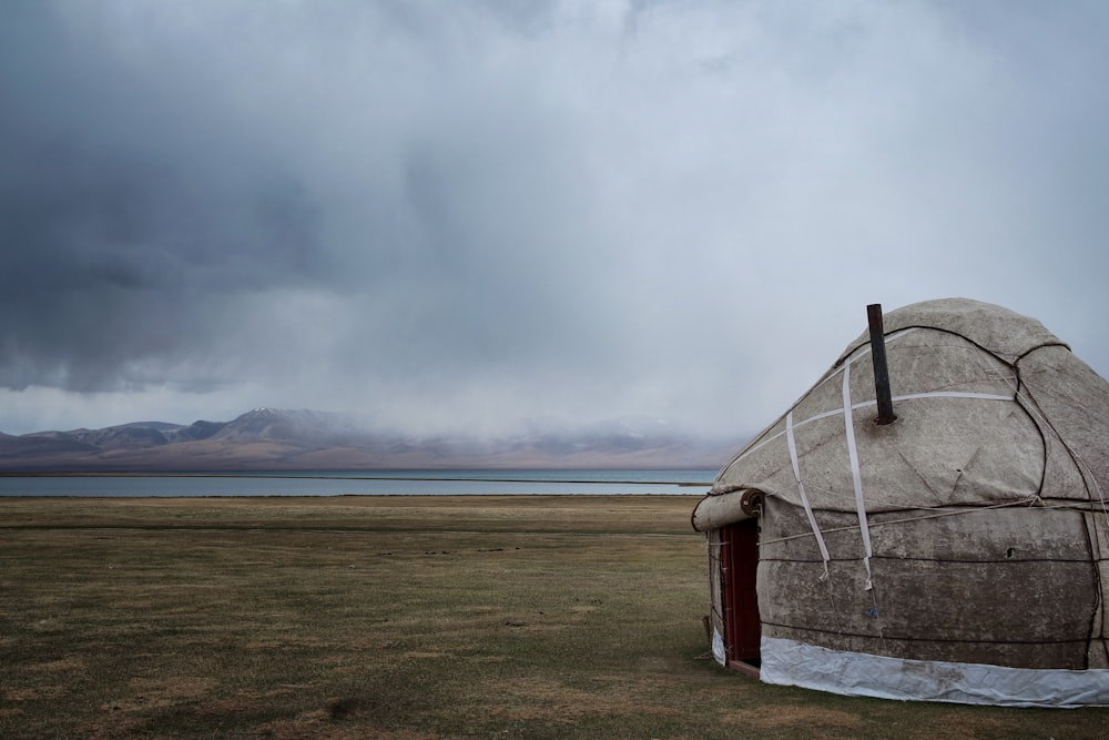 white and brown tent on green grass field under white clouds during daytime