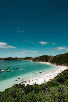 prais com pessoas na areia e barcos no mar