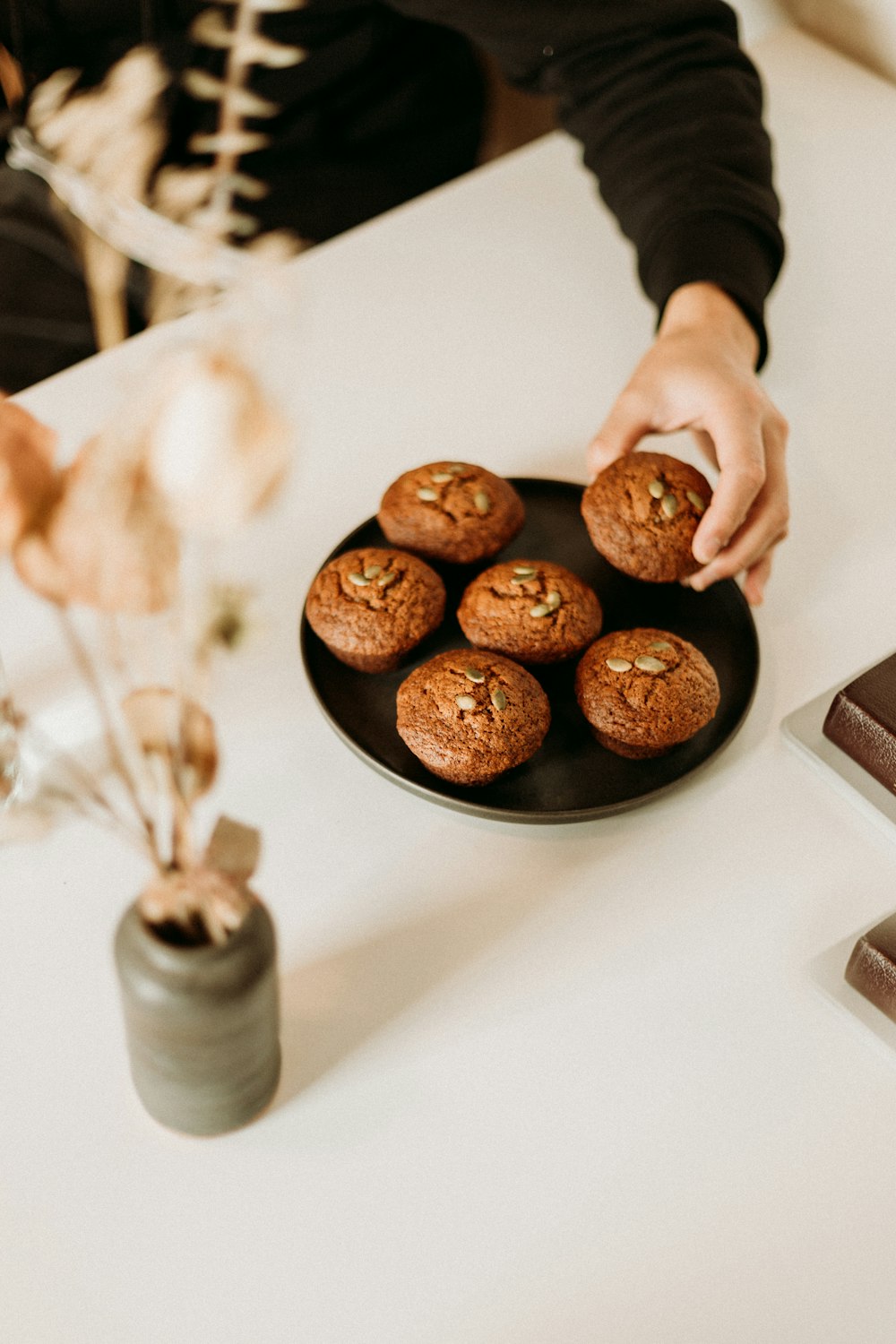 person holding black ceramic plate with cookies