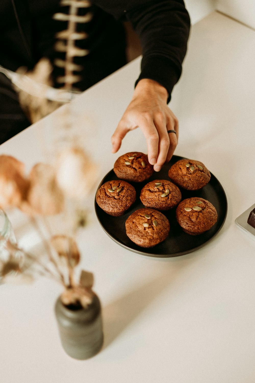 Persona che tiene il piatto rotondo nero con i biscotti