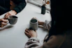 two people holding gray mugs at table