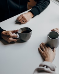 a couple of people sitting at a table with cups of coffee