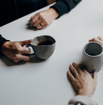 a couple of people sitting at a table with cups of coffee