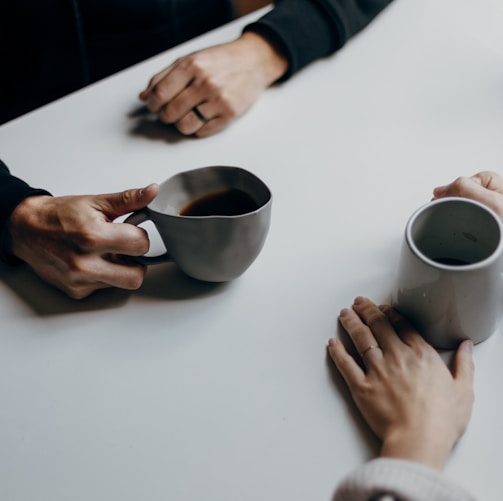 a couple of people sitting at a table with cups of coffee