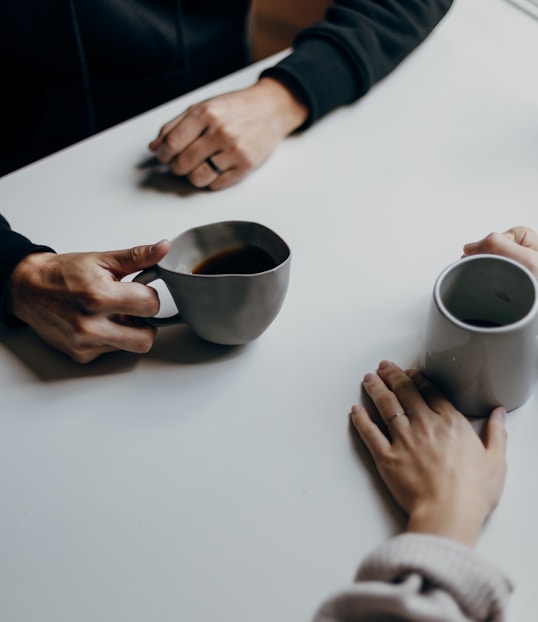 a couple of people sitting at a table with cups of coffee