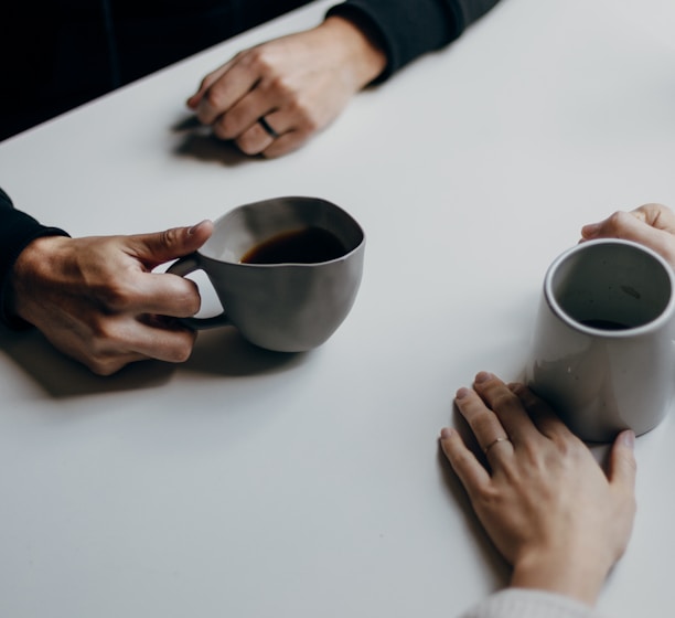 a couple of people sitting at a table with cups of coffee