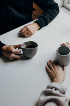 a couple of people sitting at a table with cups of coffee