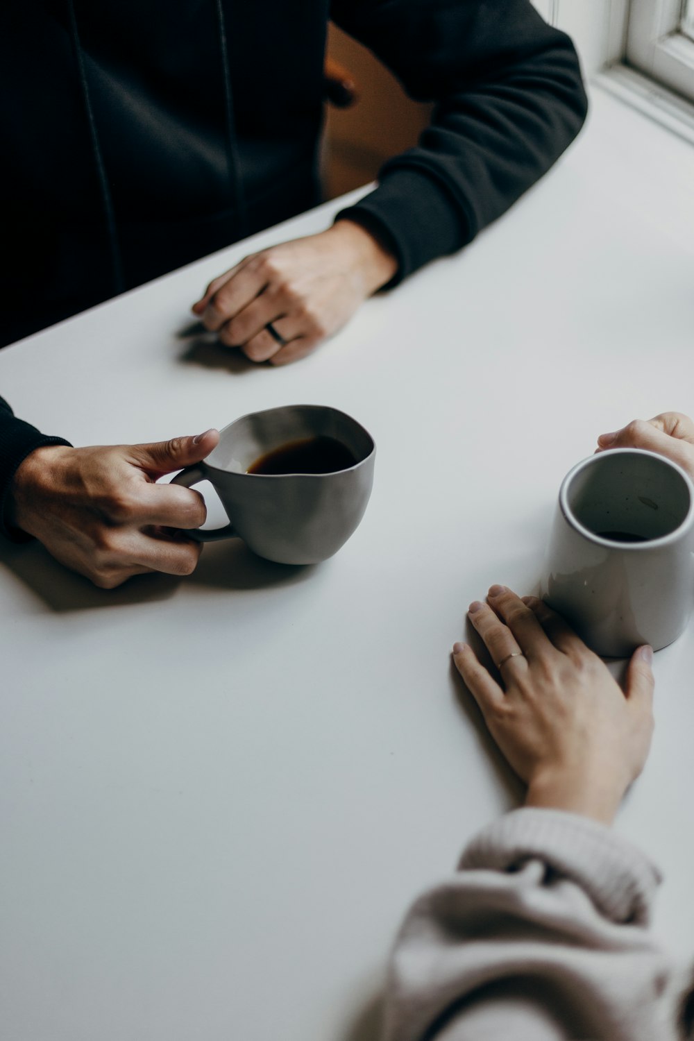 um casal de pessoas sentadas em uma mesa com xícaras de café