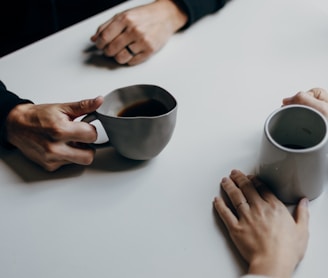 a couple of people sitting at a table with cups of coffee