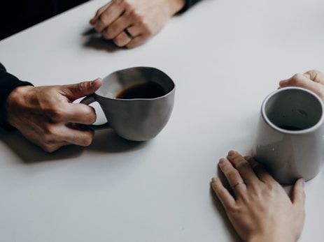 a couple of people sitting at a table with cups of coffee