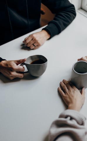 a couple of people sitting at a table with cups of coffee