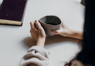 woman in white sweater holding a mug