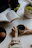 Smiling mother and daughter reading a book together at a cozy kitchen table.