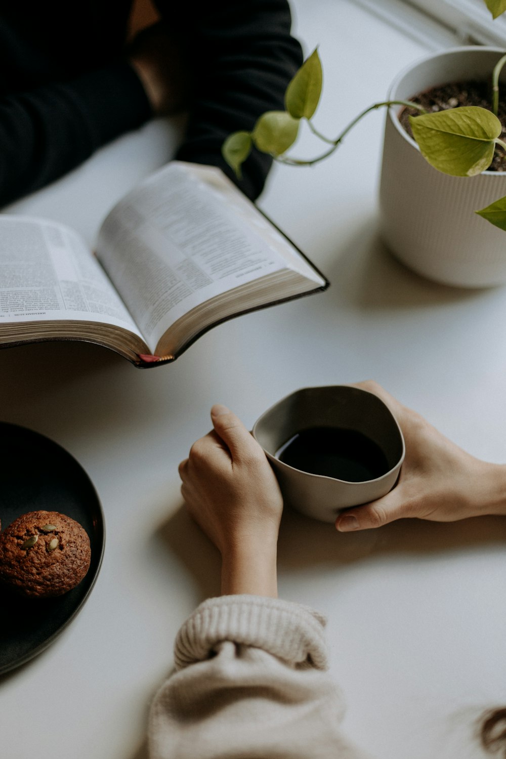 Persona che tiene la tazza di ceramica nera con il caffè