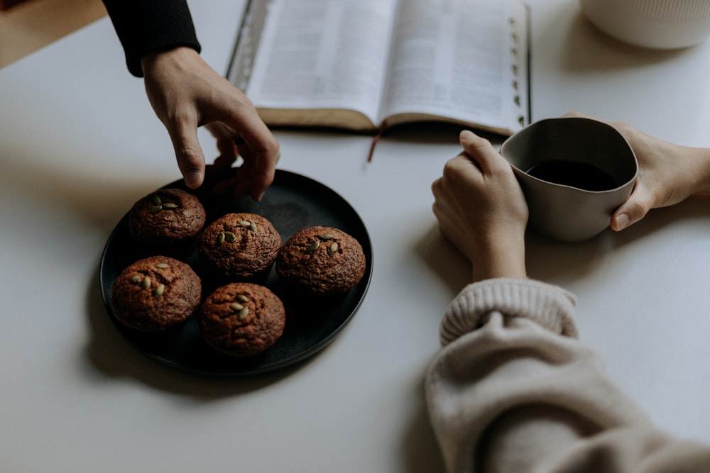 person holding black ceramic mug with coffee beans