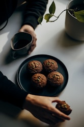 person holding black ceramic mug with coffee beans