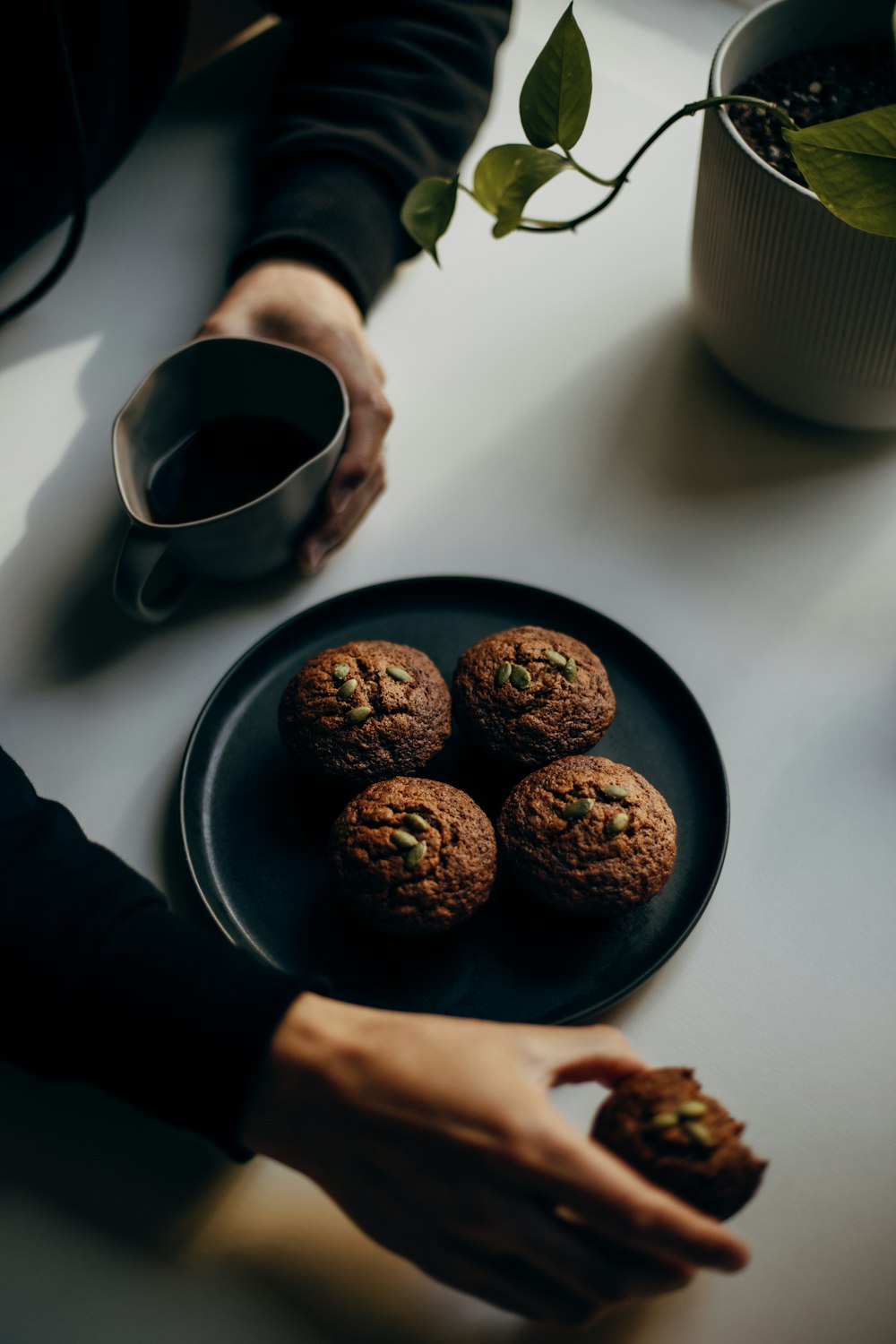 person holding black ceramic mug with coffee beans