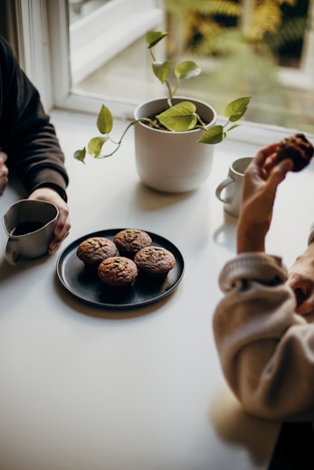 person holding brown and black round food on white ceramic plate