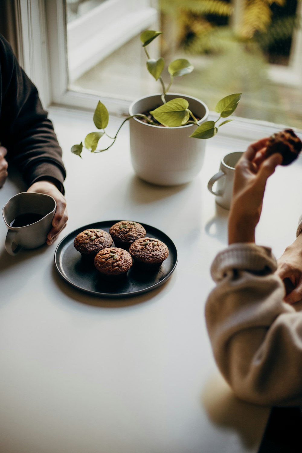 person holding brown and black round food on white ceramic plate