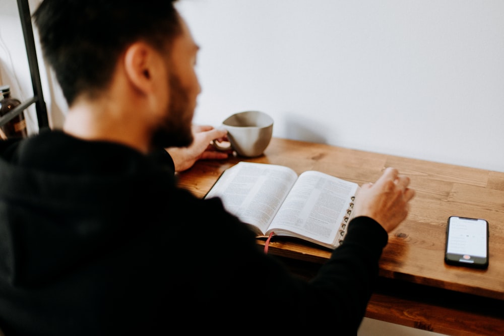 uomo in camicia nera a maniche lunghe che scrive su carta bianca