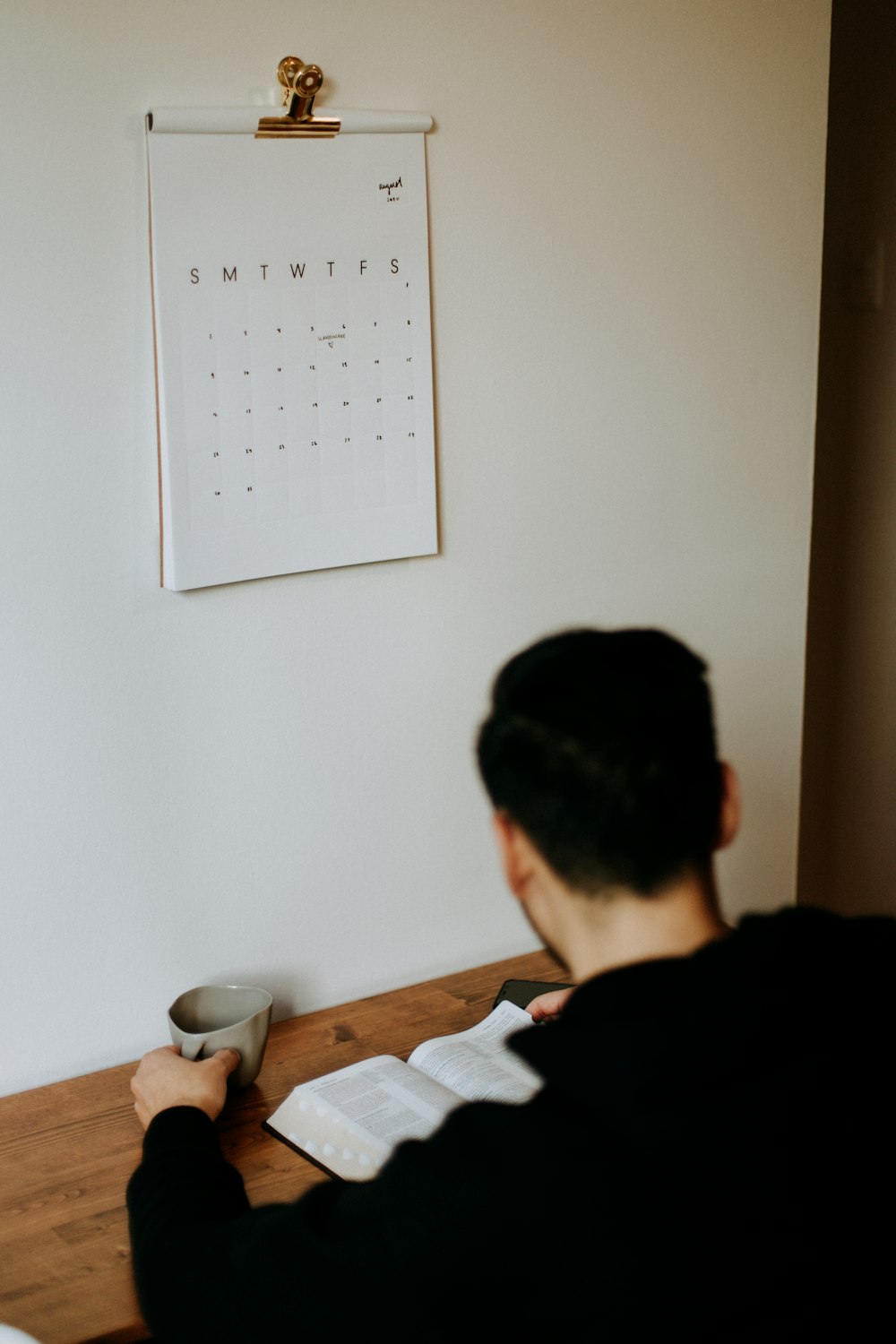 man in black shirt sitting beside brown wooden table