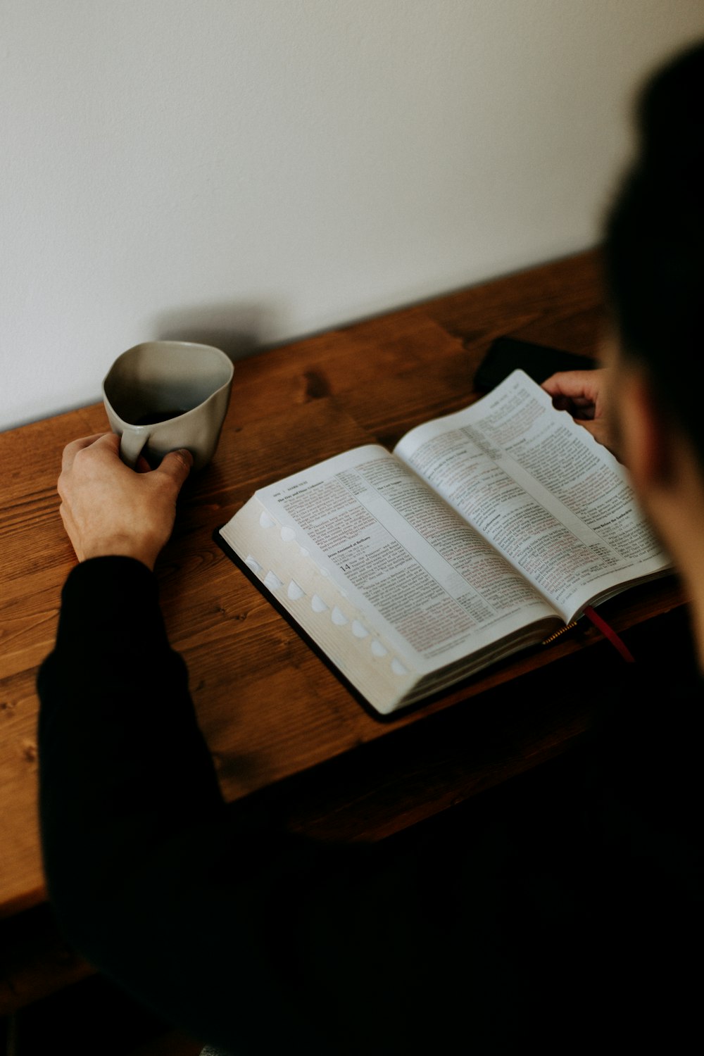 person reading book on brown wooden table