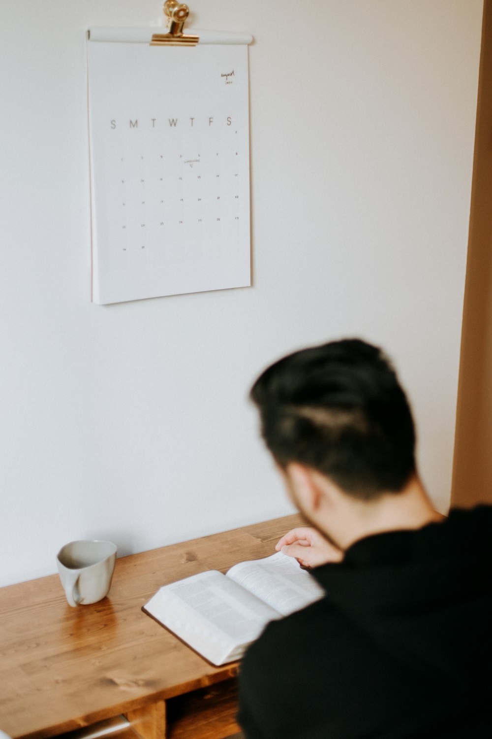 um homem sentado em uma mesa com um livro aberto