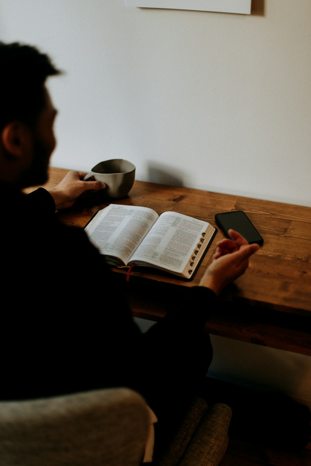 hombre con camisa negra leyendo libro