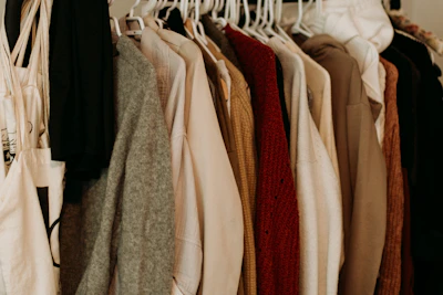 Rows of finished sustainable garments hanging on wooden racks in a bright studio.