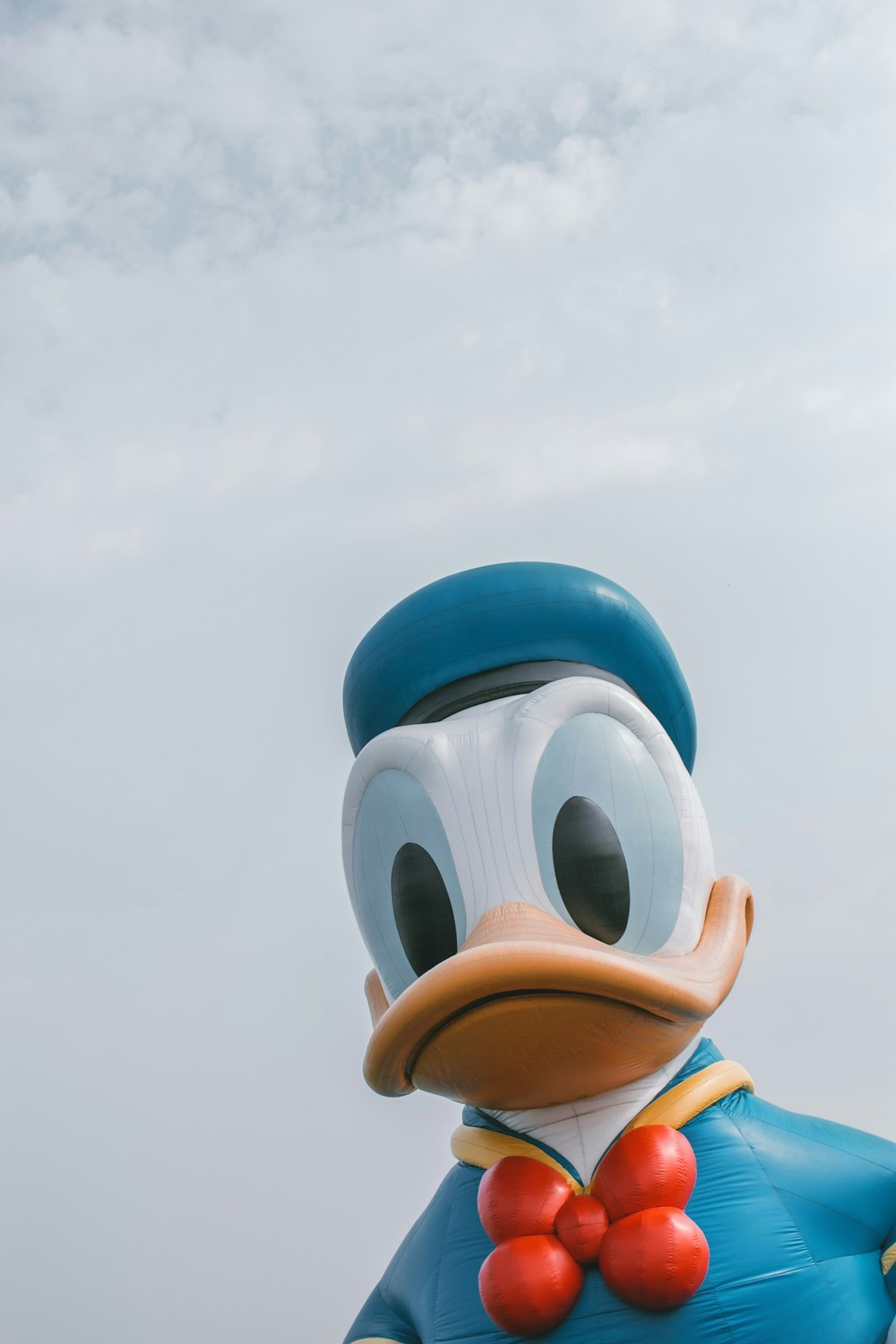 a large duck with a bow tie standing in front of a cloudy sky