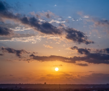 silhouette of mountain under cloudy sky during sunset