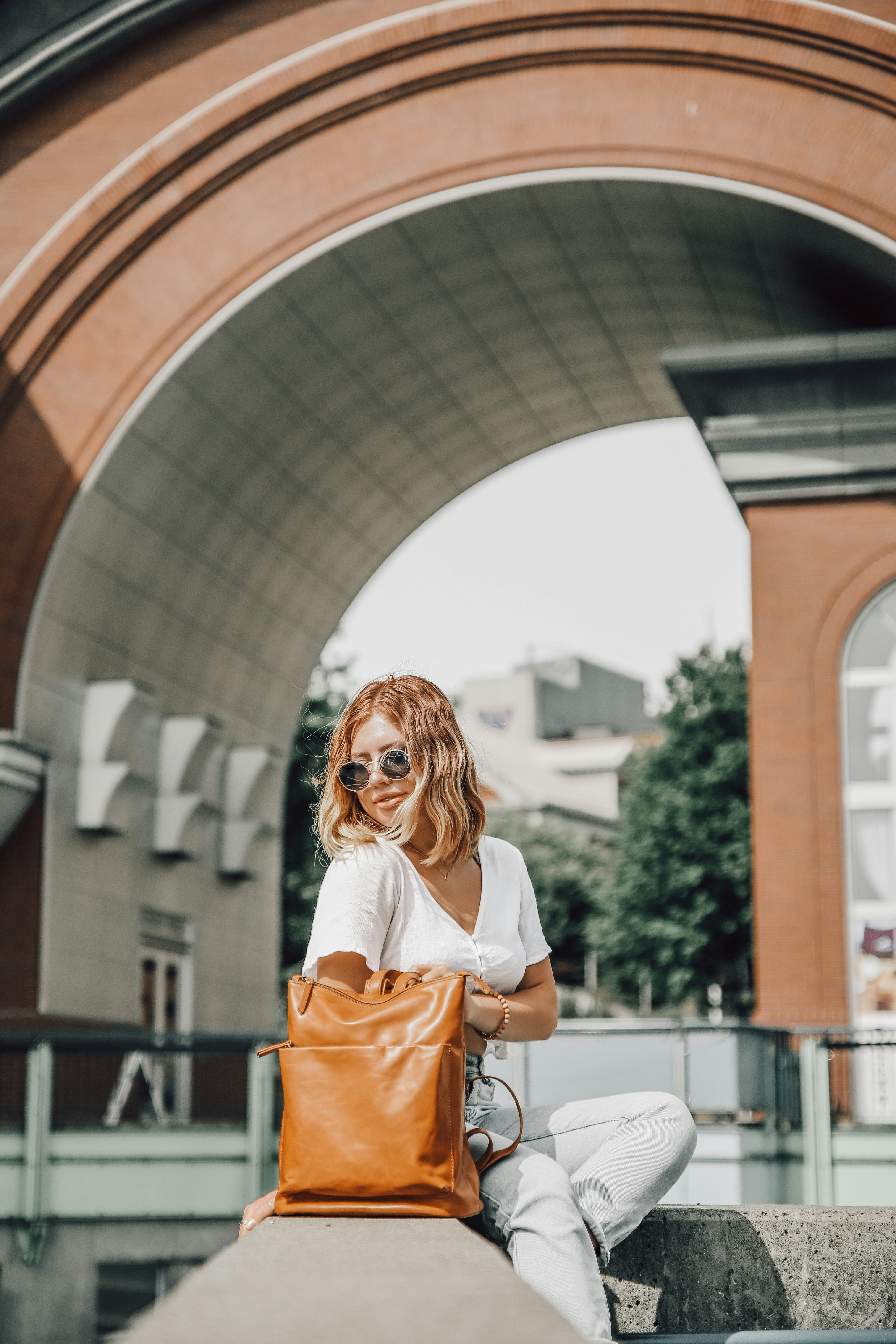 woman-in-white-long-sleeve-shirt-standing-near-brown-concrete-building-during-daytime