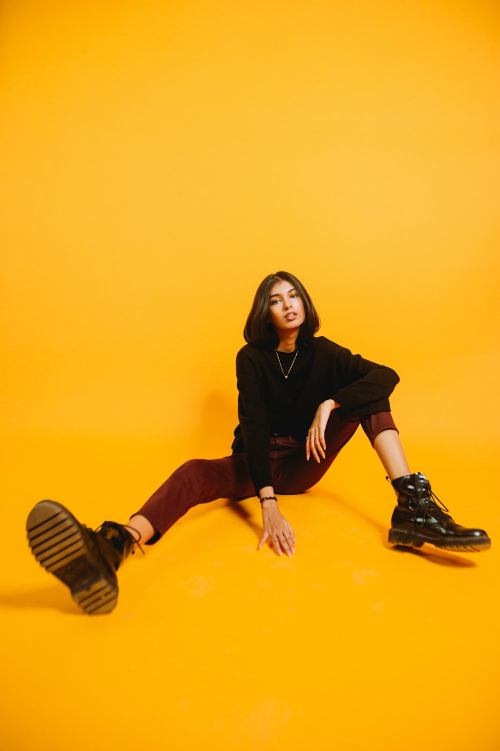 woman in black long sleeve shirt and black pants sitting on yellow floor