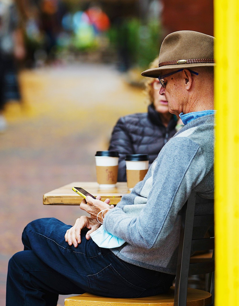 man in blue denim jacket and brown cowboy hat sitting on yellow chair