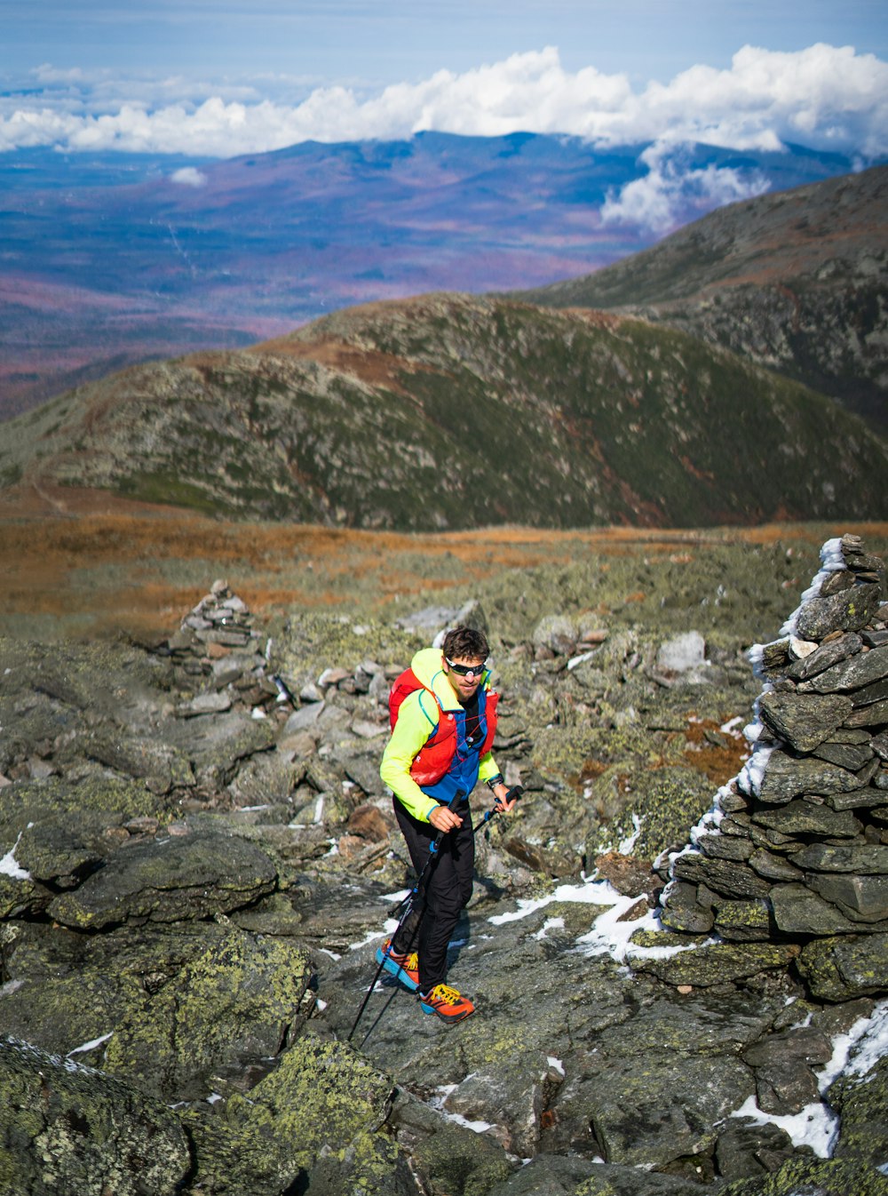 man in blue jacket and orange pants standing on rocky ground during daytime