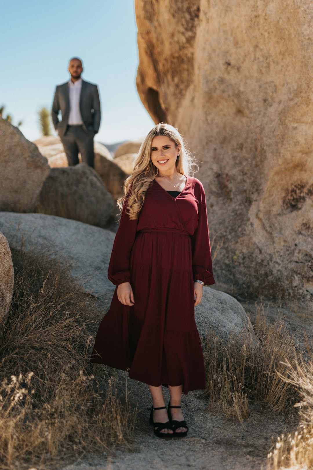 woman in red long sleeve dress standing on brown rock during daytime