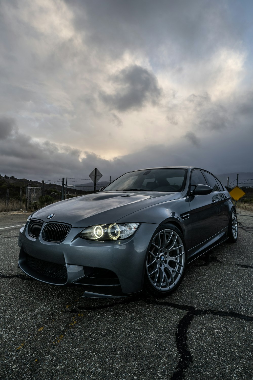 BMW M 3 coupé noir sur route sous des nuages gris
