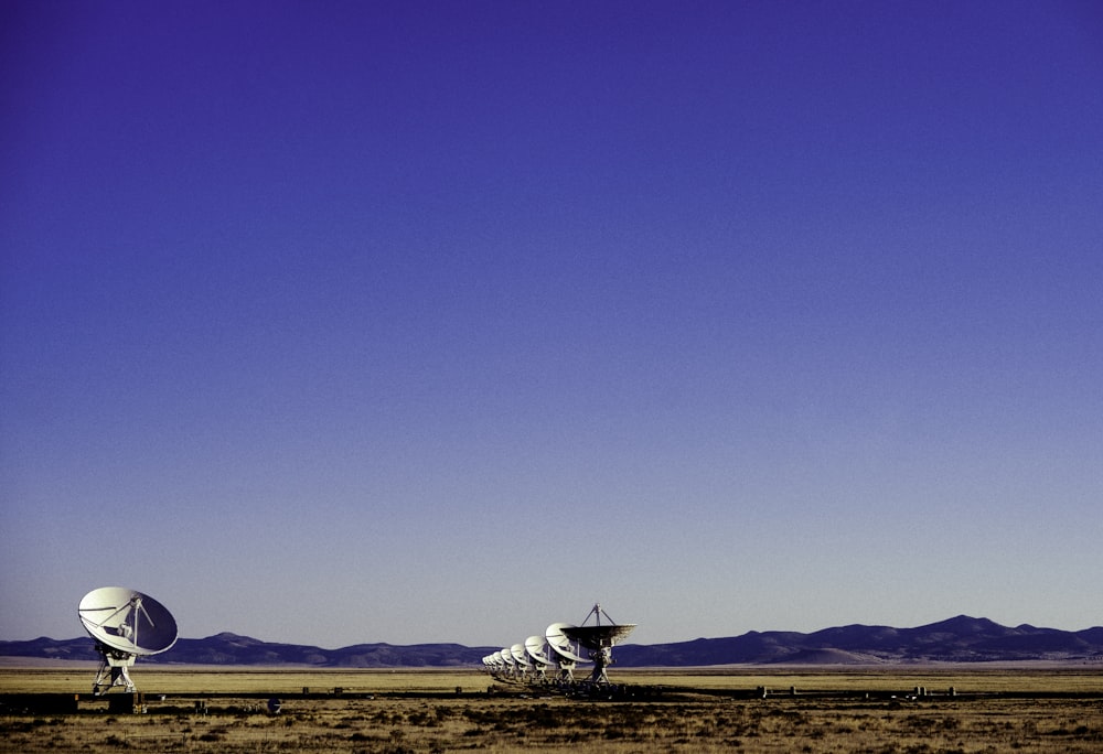 white and black windmill on brown field under blue sky during daytime