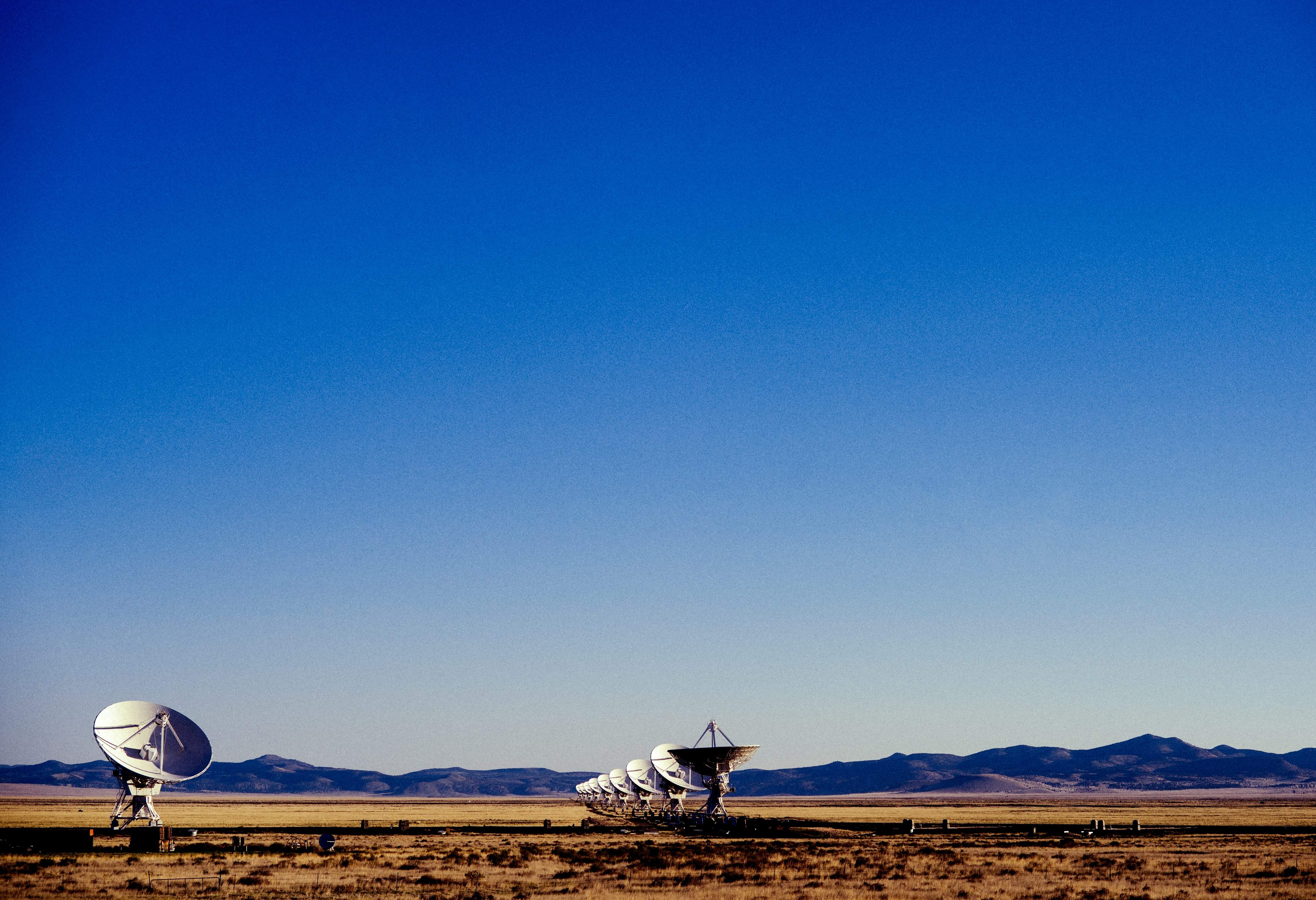 white and black windmill on brown field under blue sky during daytime