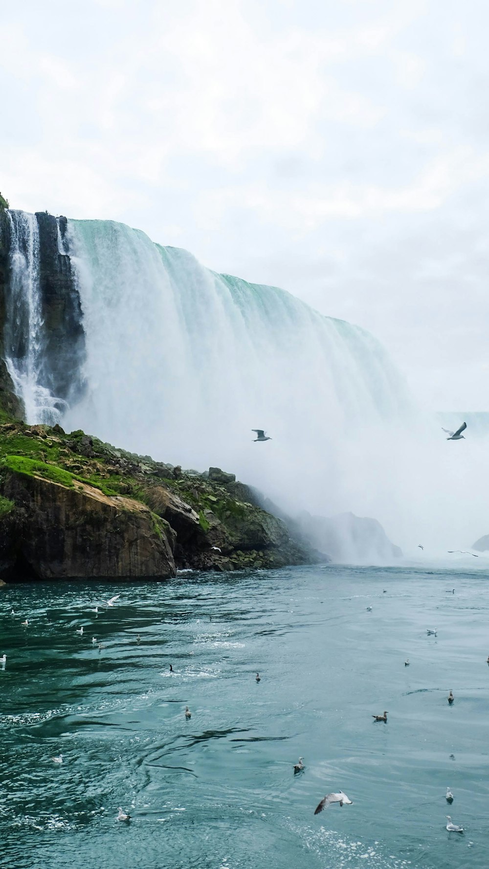 people standing on cliff near waterfalls during daytime