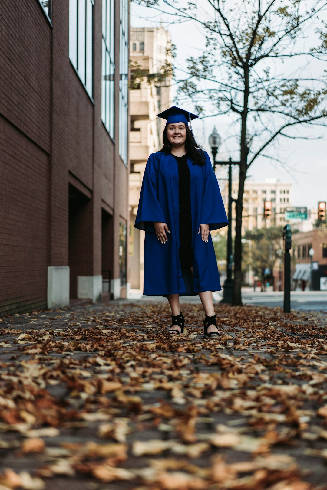 woman in blue academic dress standing on brown dried leaves during daytime
