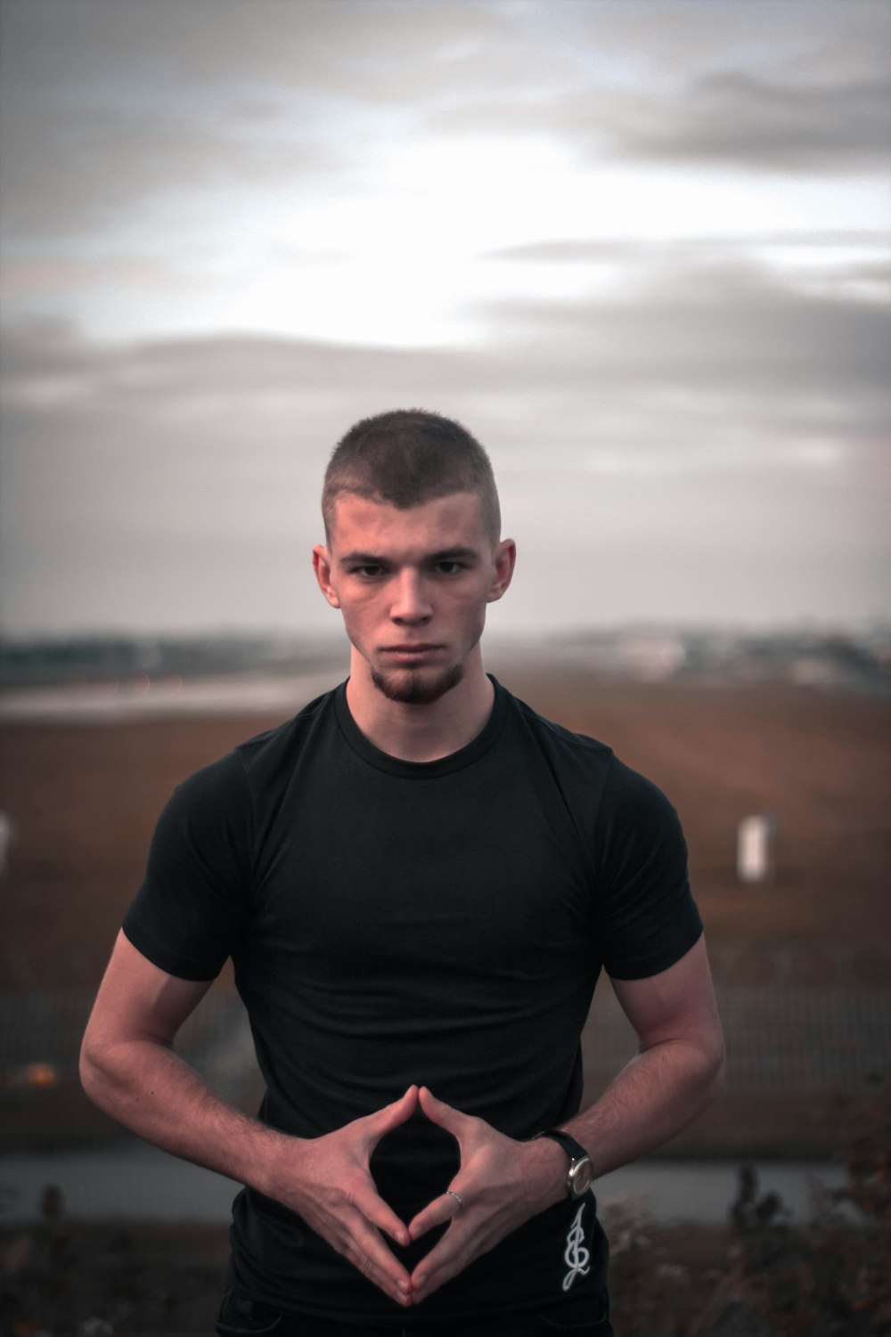 man in black crew neck t-shirt standing on brown field during daytime