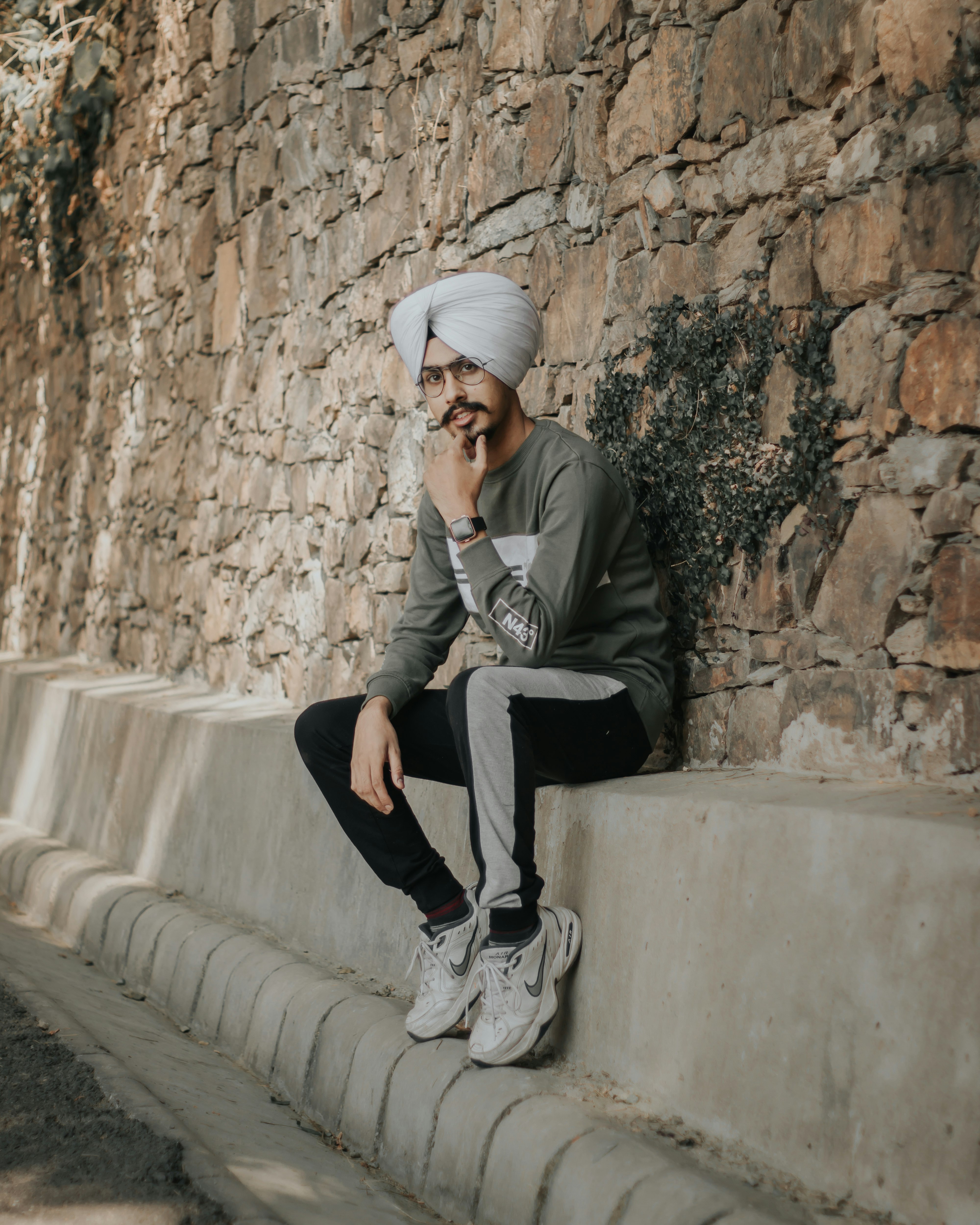 man in gray jacket and black pants sitting on gray concrete bench