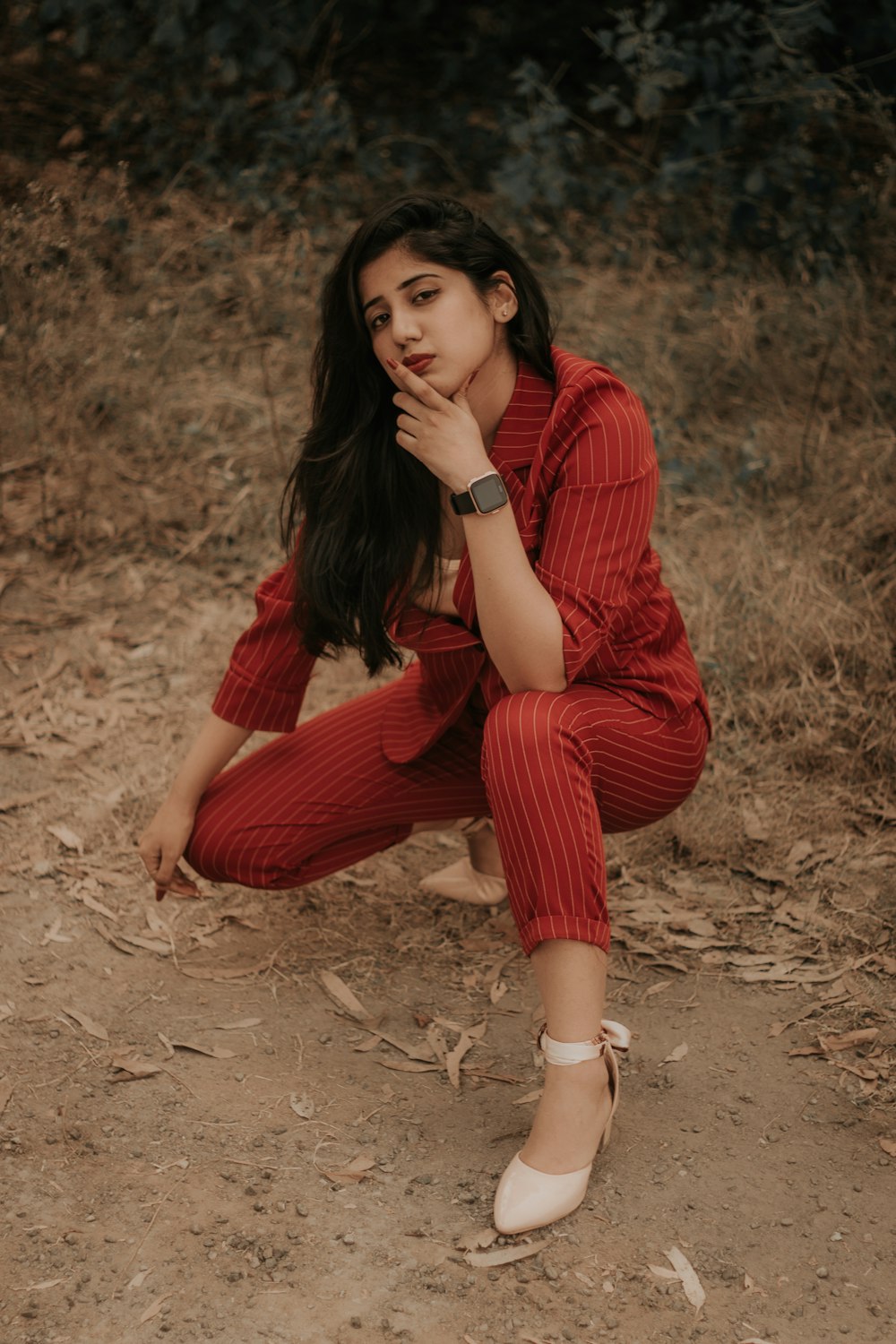 woman in red long sleeve shirt and red skirt sitting on brown sand during daytime