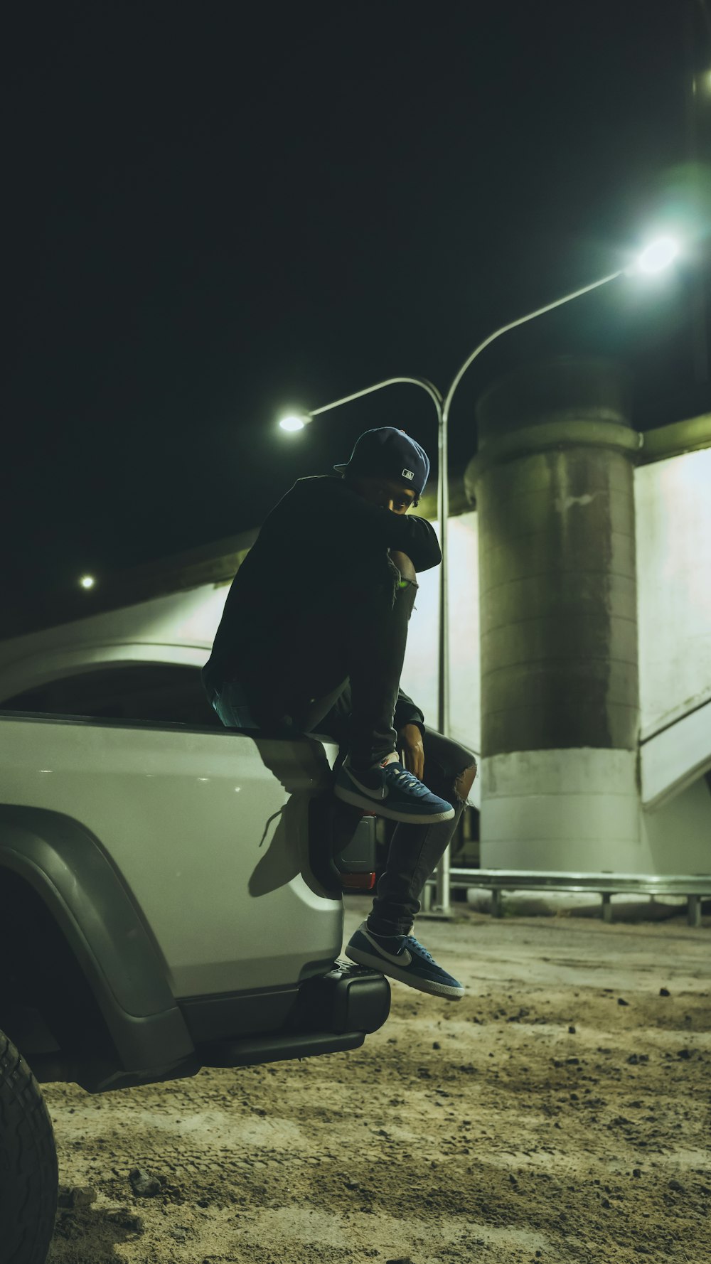 man in black jacket and black pants sitting on white car